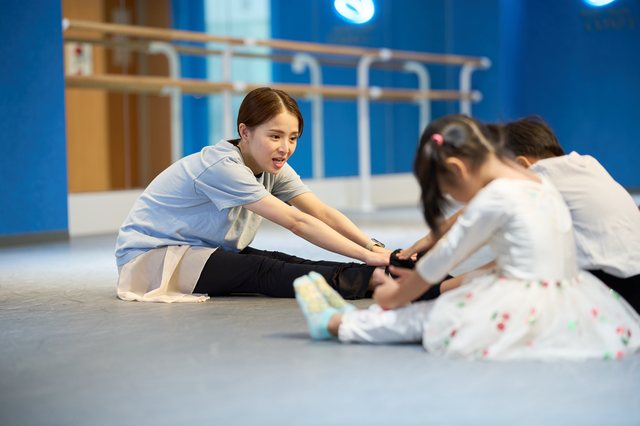 講師と幼児が床に座って一緒に足先ストレッチ